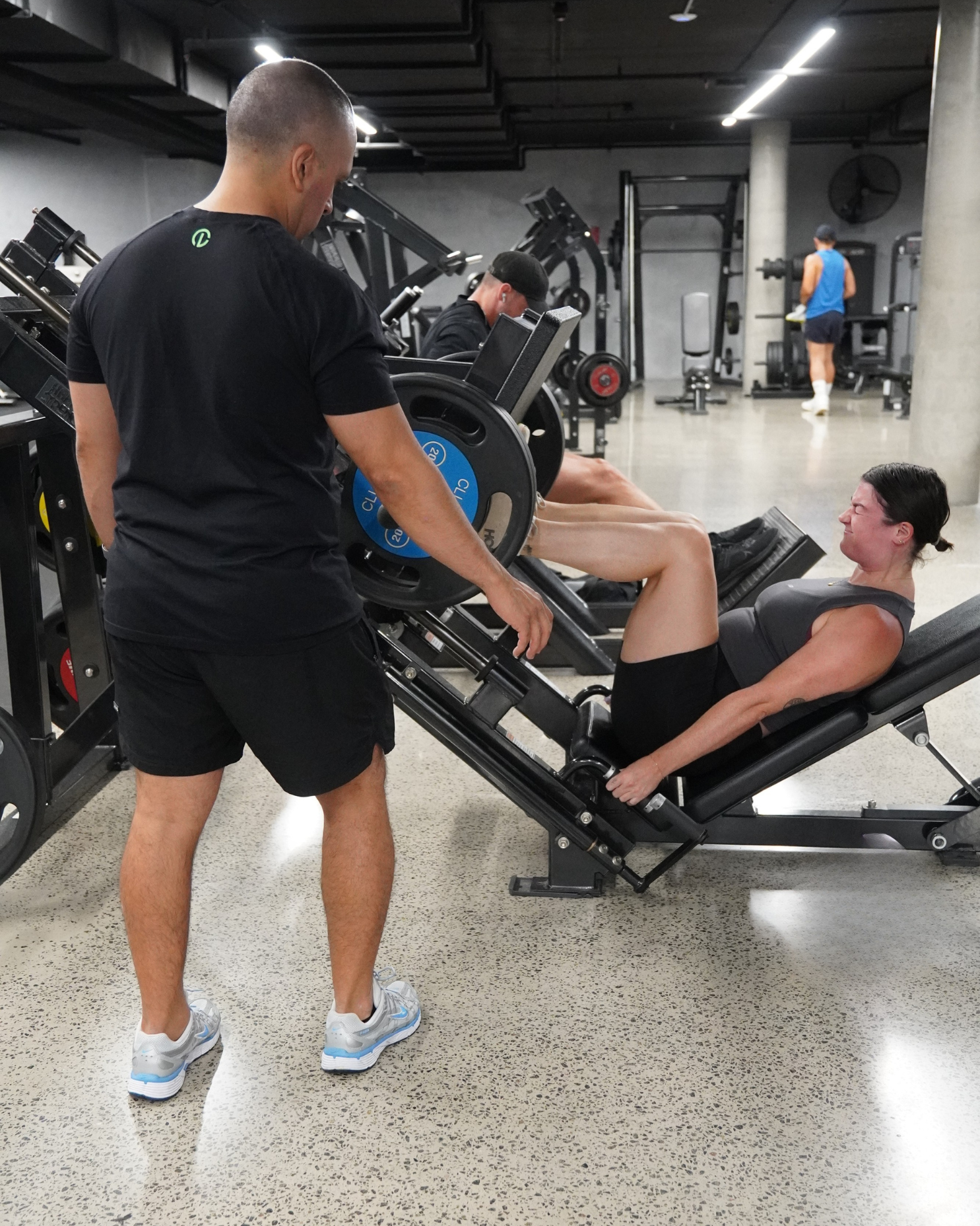 Carlos coaching a client on the leg press